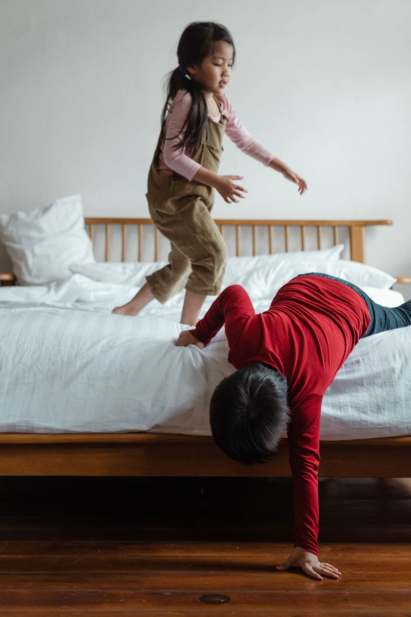 Zwei Kinder lachen beim Spielen auf einem Bett
