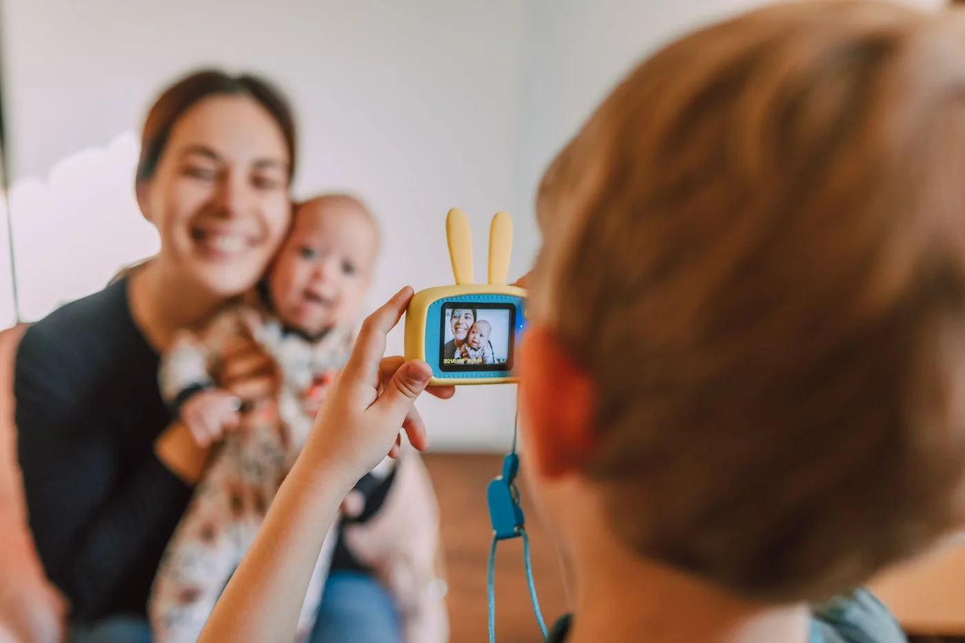Ein Kind fotografiert eine Frau mit Baby